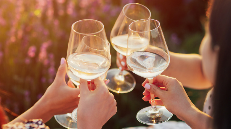 Four people toasting glasses of white wine