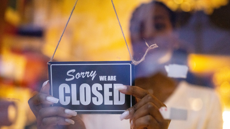 Restaurant employee placing closed sign on door