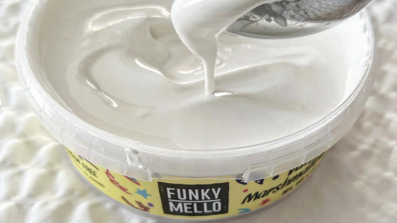 A spoon being dipped into a container of Funky Mello marshmallow creme