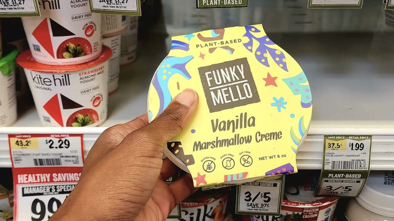 A hand holding a container of Funky Mello marshmallow creme at a Whole Foods