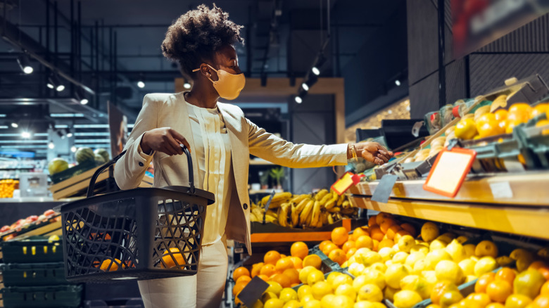 Customer wearing a mask shopping in the grocery store produce section
