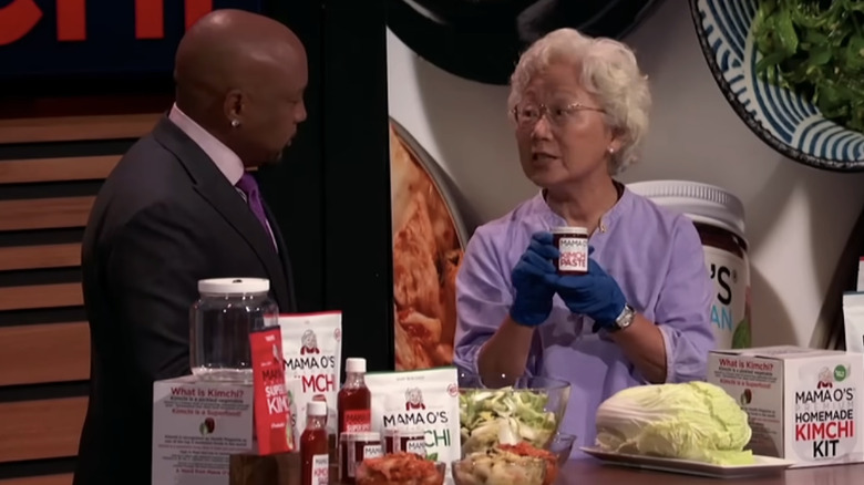 An elderly Korean woman showing off her kimchi to Daymond John on Shark Tank