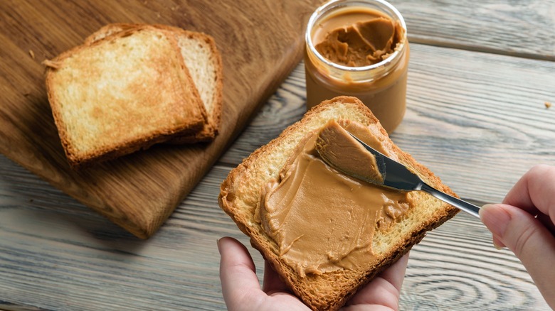 Spreading peanut butter on toast