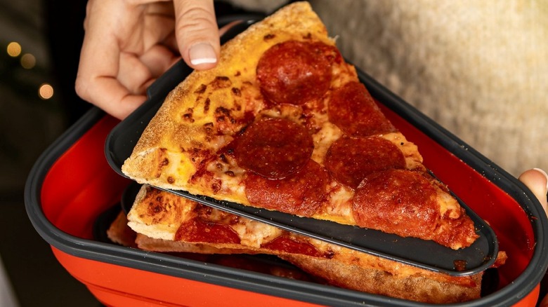 Person removing slice of pizza from Pizza Pack container