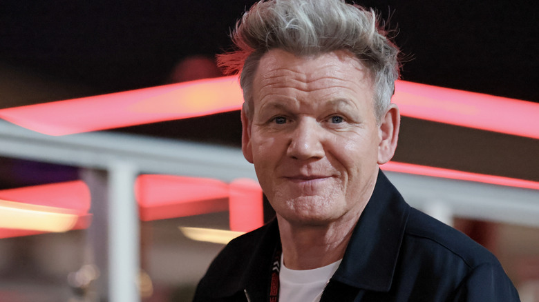 Gordon Ramsey smiling outside in front of neon