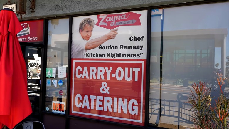 A window display of Zayna Flaming Grill with a picture of Gordon Ramsay from Kitchen Nightmares.