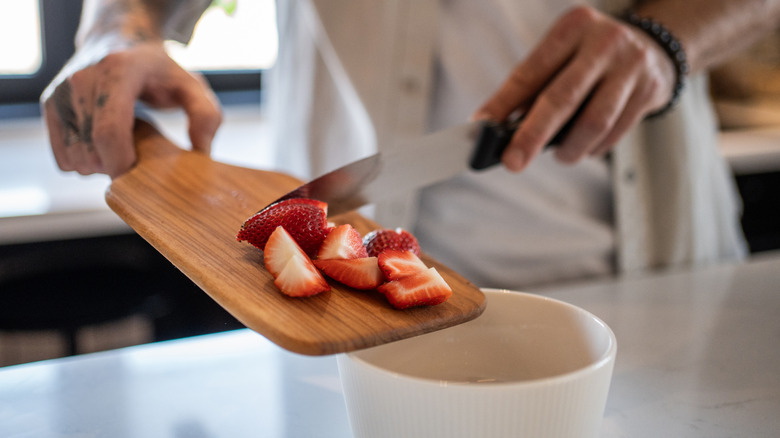 Sliding chopped strawberries  into bowl