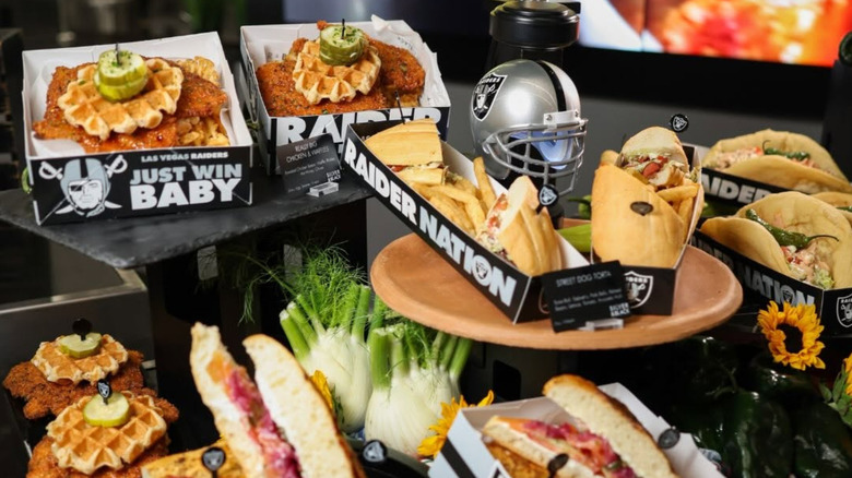 Sandwiches, chicken and waffles, and other food items in Raider Nation boxes on a display platter.