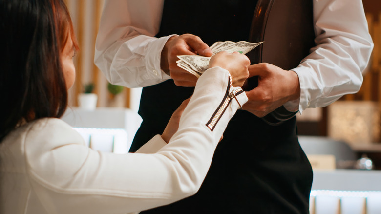 Customer handing server cash at a high-end restaurant