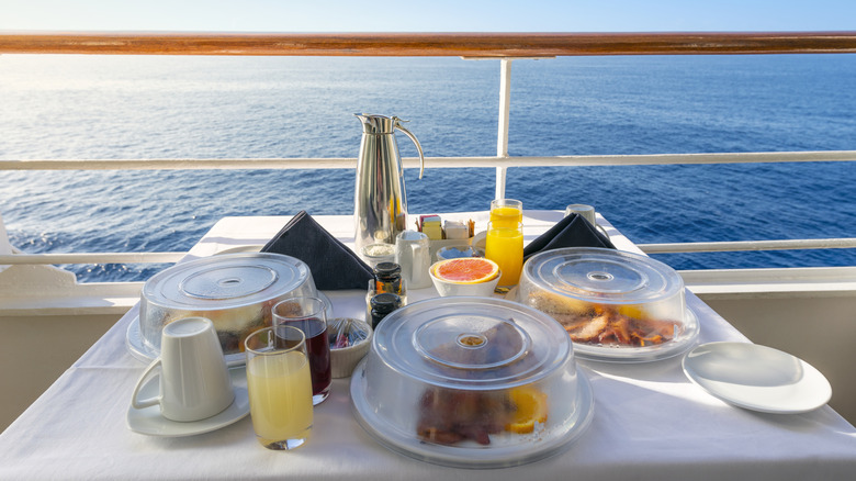A breakfast meal covered with clear plastic lids on a cruise ship deck