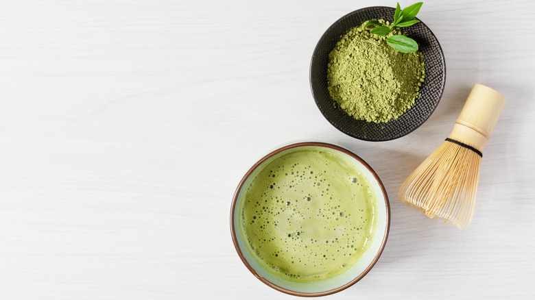 Cup of organic matcha tea with bowl of matcha powder