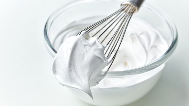 A whisk over a bowl of whipped egg whites