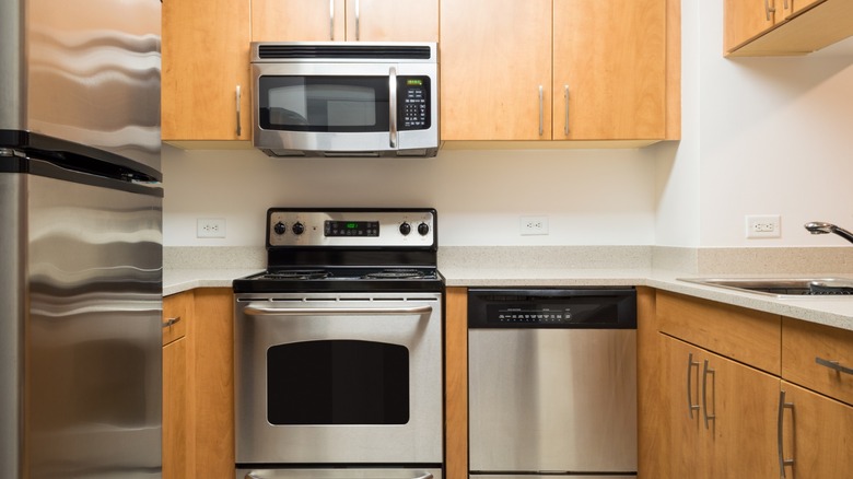 White kitchen with wood cabinets and chrome appliances.