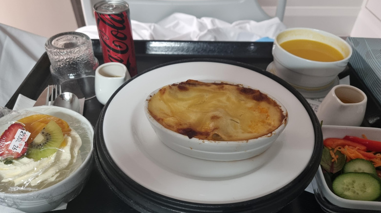 Hospital tray with lasagne, pumpkin soup, salad, pavlova, and Coca-Cola.