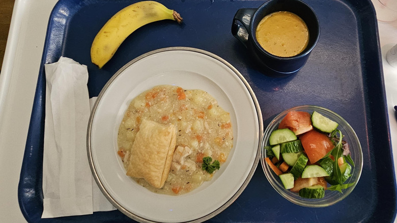 Hospital tray with chicken casserole, pastry, pumpkin soup, side salad, and banana.