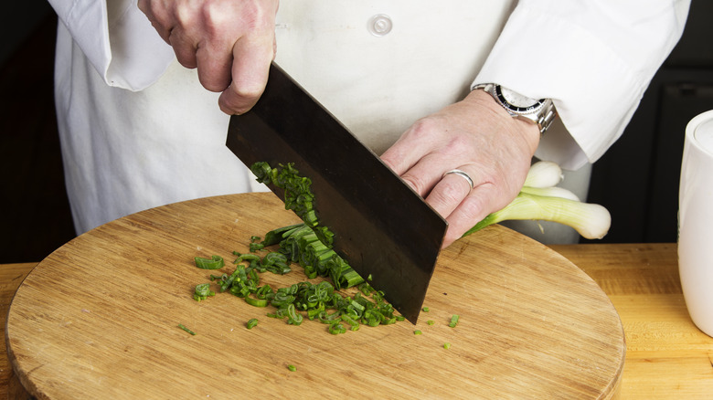 person cutting scallions with cleaver