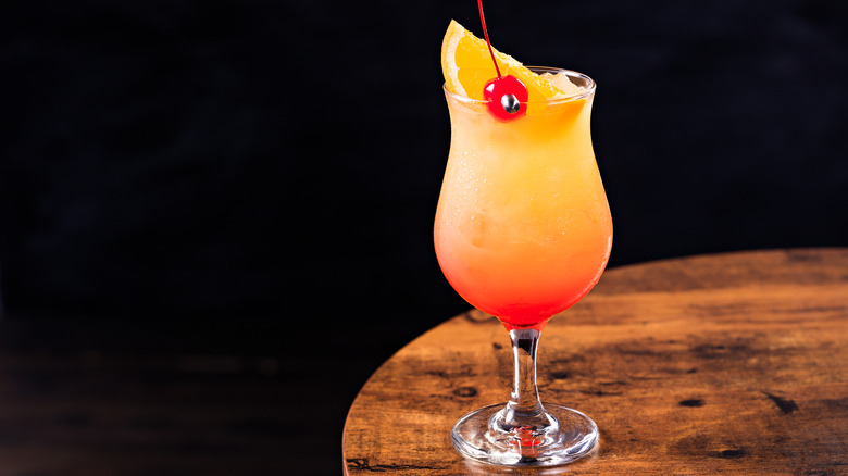 A hurricane cocktail sitting on a table. 