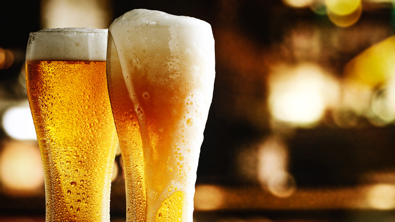 Two pint glasses full of foamy light beer