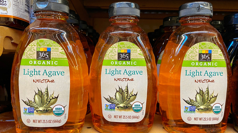 Three bottles of agave nectar on a shelf