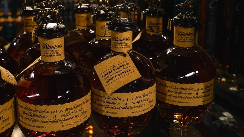 Multiple bottles of Blanton's original bourbon sitting on a shelf in storage.