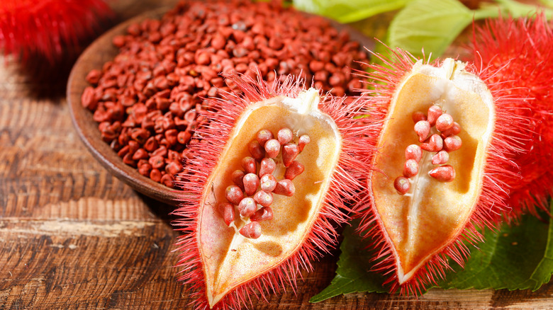 Annatto seeds in bowl and whole fruit