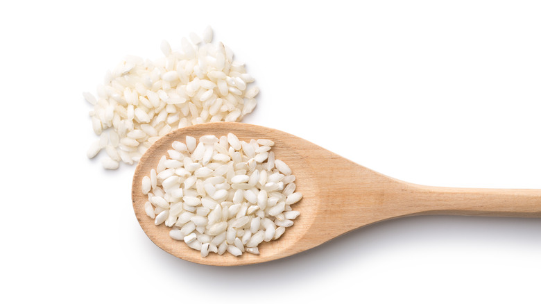 Closeup of white arborio rice in wooden spoon