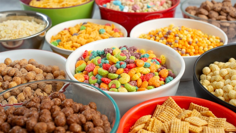 Multiple bowls of assorted popular breakfast cereals.
