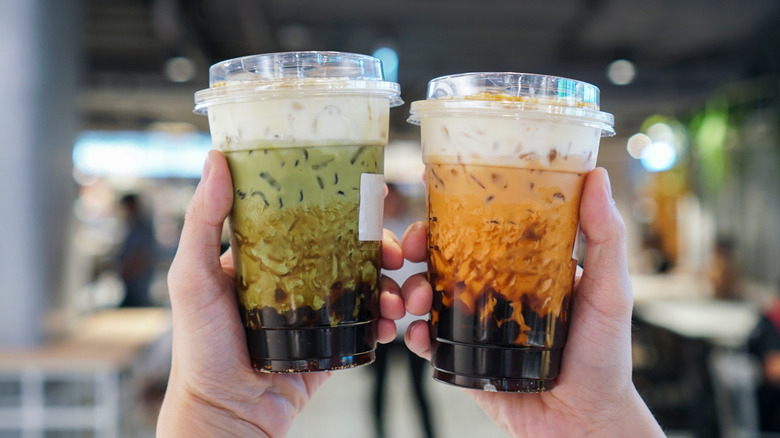 Hands holding two iced boba teas