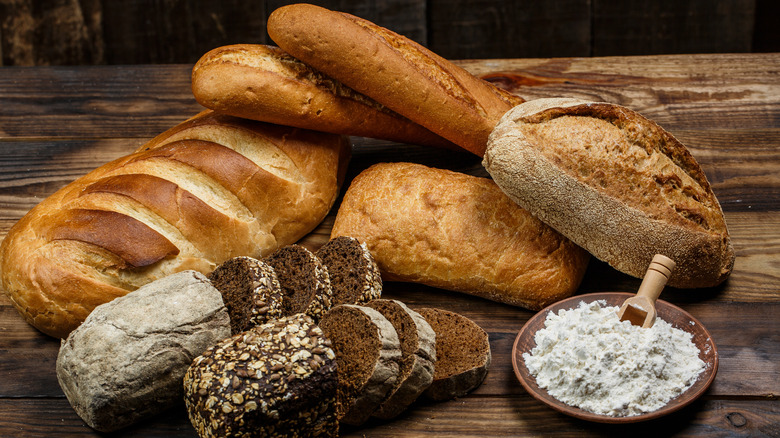 Loaves of bread and a bowl of bread flour on a table