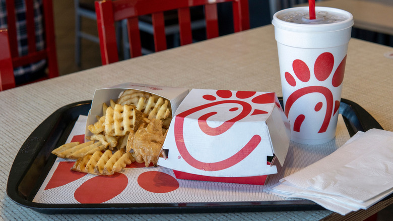Chick-fil-A tray with fries, sandwich box, and drink on restaurant table.