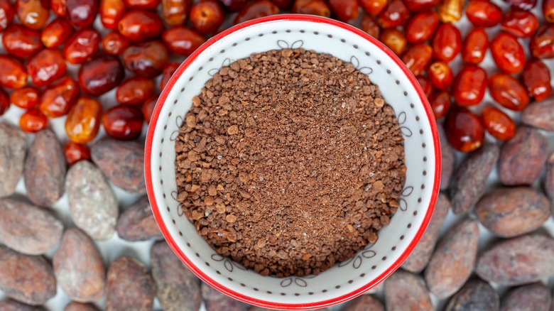 Ground chiltepin in a bowl next to whole chiltepin