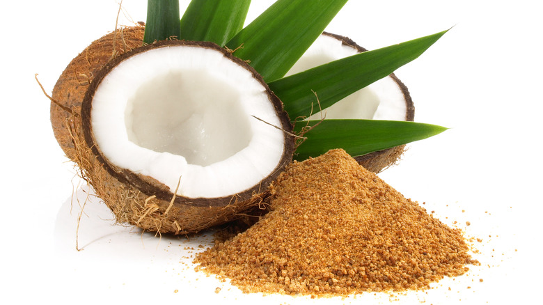 Cut open coconut next to pile of coconut sugar