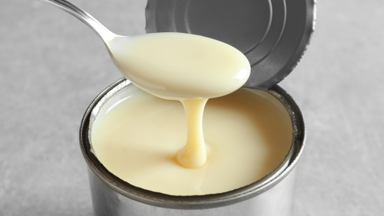 Open can of condensed milk with spoon