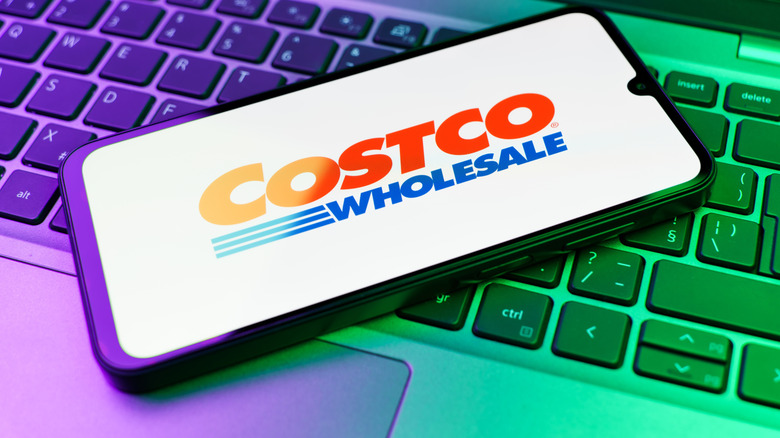 Costco Wholesale image on phone screen atop laptop keyboard
