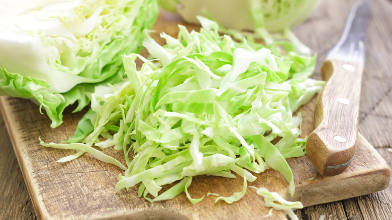 Chopped cabbage and knife on wood cutting board