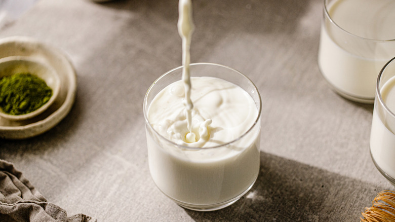 Milk pouring into a glass on a light gray thatched tablecloth
