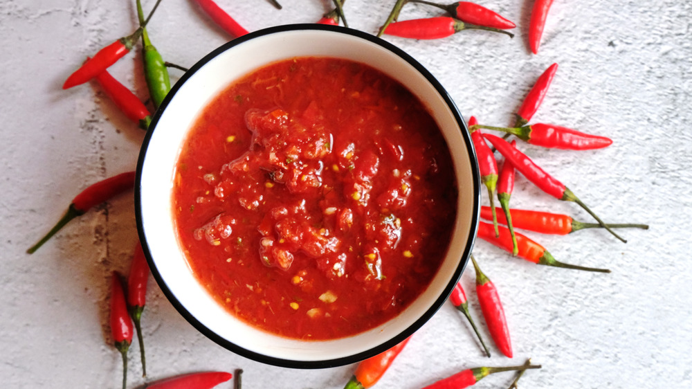 Harissa in a bowl surrounded by chilis