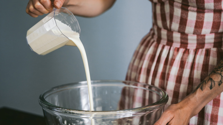 Young woman pouring heavy cream into a bowl 