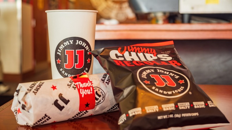 Drink, chips, and sandwich from Jimmy John's on restaurant table.