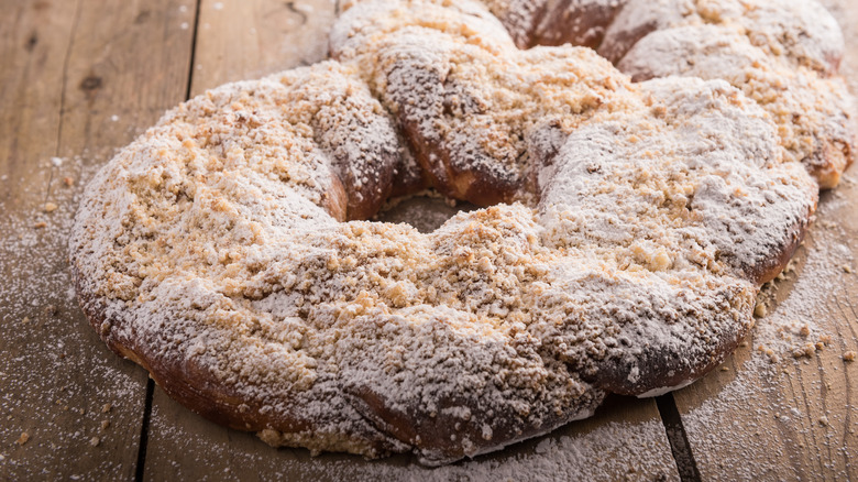 Kringle covered with crumbs on wood surface