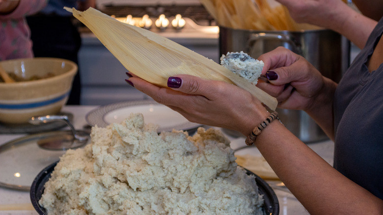 Person spreading masa on tamale husks