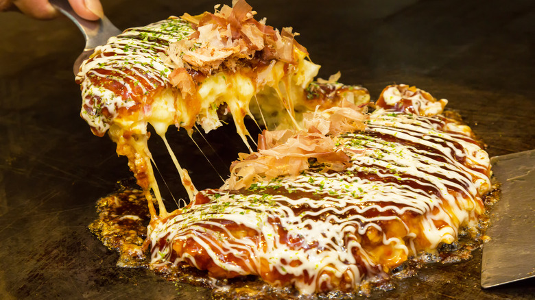 A slice of okonomiyaki lifted from grill