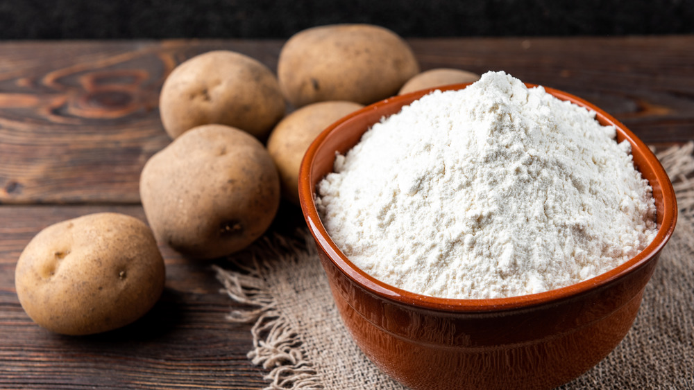 Potato starch with bowl on table with potatoes 