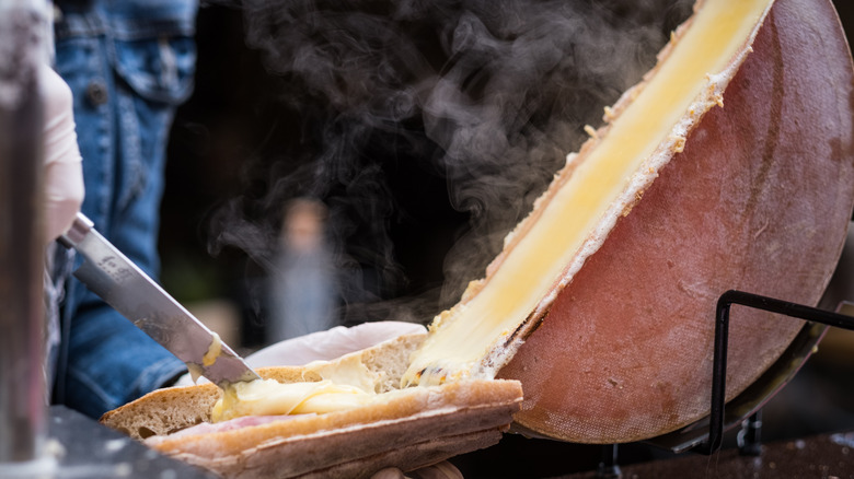 Hot raclette cheese scraped off wheel onto bread
