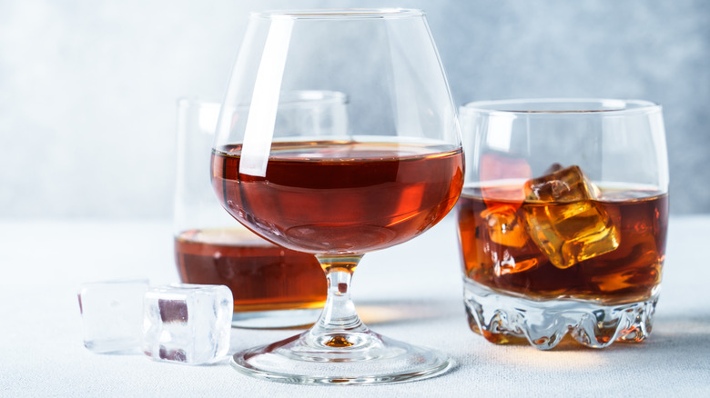 Rum in glasses with ice on light blue background.