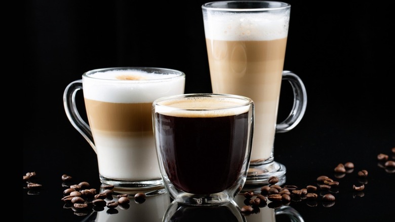 Various glass mugs of coffee on black background