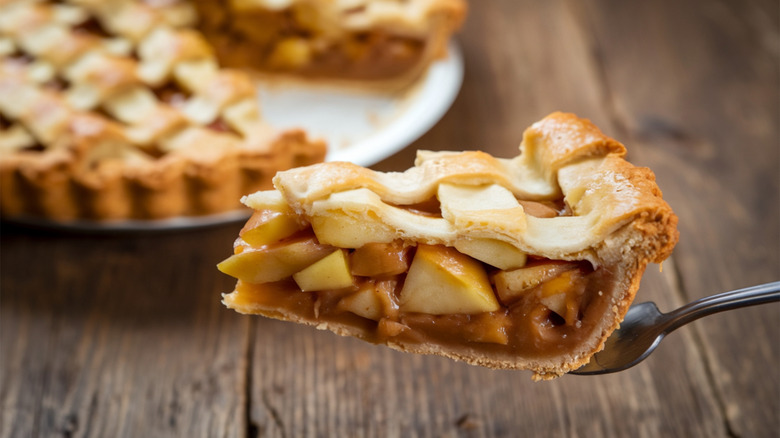 Slice of apple pie with lattice crust on metal spatula.