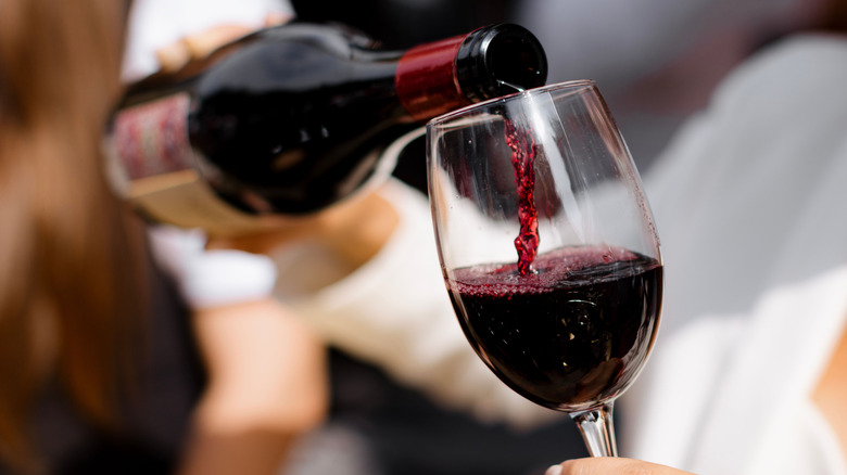 Red wine pouring from bottle into glass.
