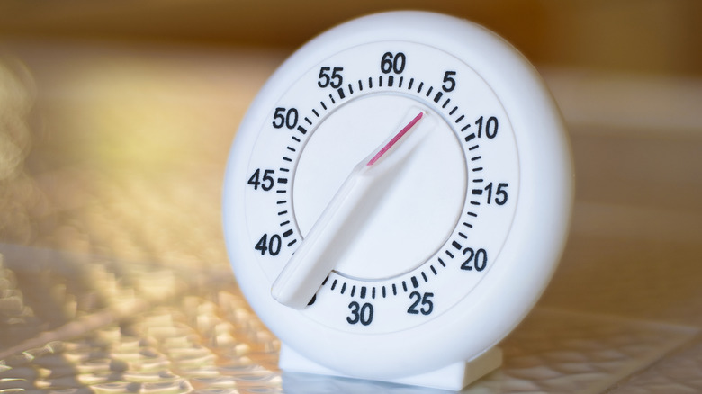 Close-up of white kitchen timer on white tile countertop.