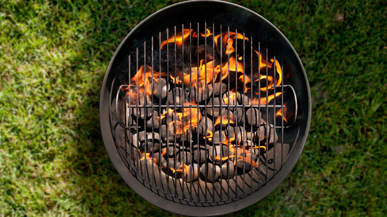 Overhead view of charcoal grill with burning coals on grass